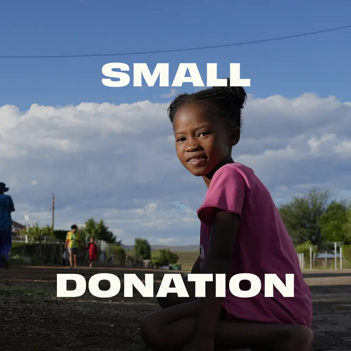 Young girl in a pink shirt sitting outdoors with 'SMALL DONATION' text overlay.